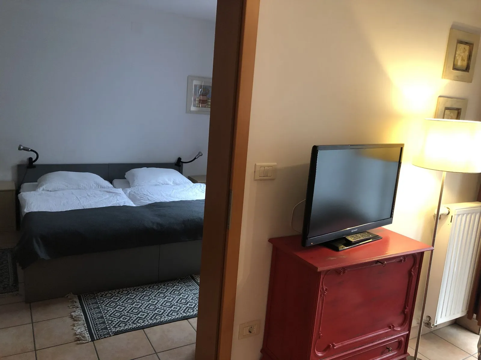 Postelja, televizor in rdeča komoda